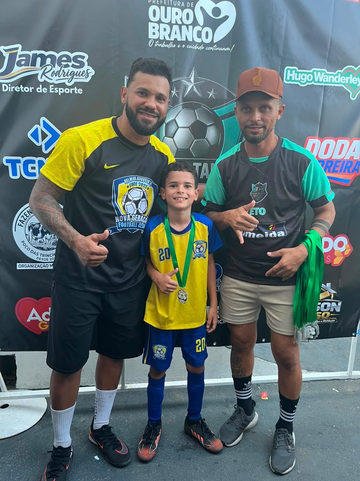 Atleta premiado posando com professores e medalha